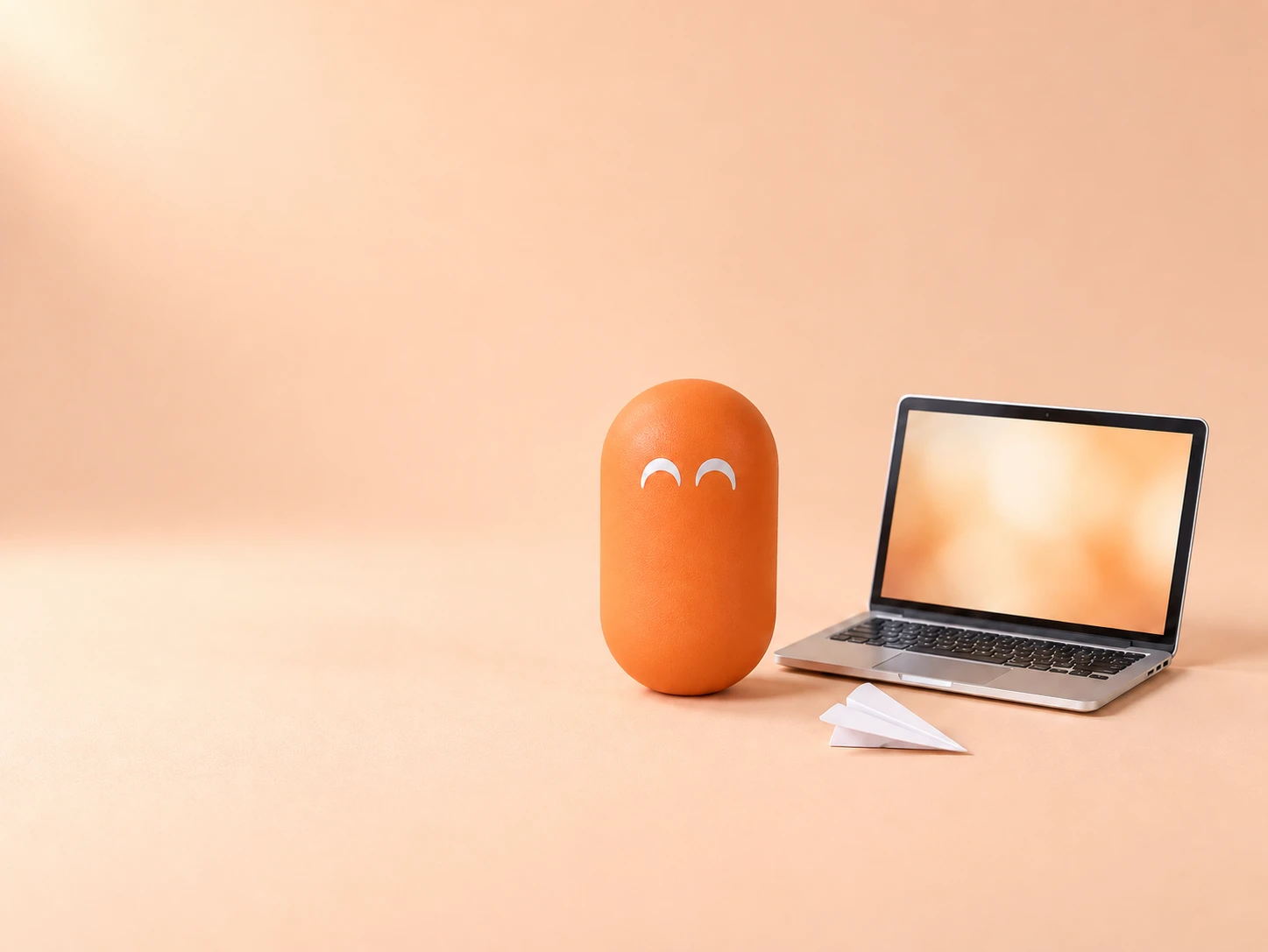 A smiling orange pill next to a tiny laptop and a paper airplane, as if it had just sent a message.